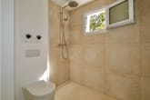 Innenansicht Badezimmer mit bodengleicher Duschecke in Natursteinoptik Handbrause WC und Pflanzennische