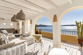Blick auf überdachte Meerblick-Terrasse mit Rattanmöbeln und Rundbogenarkaden