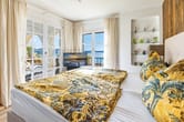 Schlafzimmer mit Doppelbett aus Innenperspektive und offener Balkon mit Meerblick