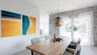 Moderner Essbereich mit Holztisch, sechs gepolsterten Stühlen, Hängeleuchte, Steinakzentwand und bodentiefen Glastüren