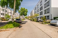 Calle residencial tranquila con viviendas bien cuidadas y mucha vegetación