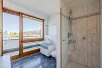 Zeitlos gefliestes Bad mit Dusche und hellem Fensterbereich