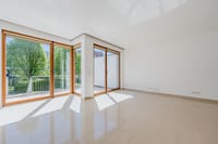Weitläufiger Wohnbereich mit bodentiefen Fenstern und Blick ins Grüne