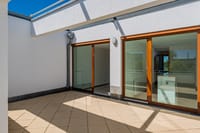 Dachterrasse mit großflächiger Verglasung und direktem Zugang zum Wohnbereich