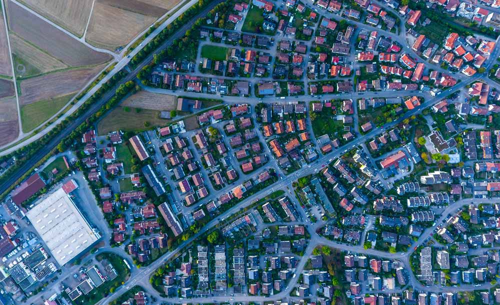 Luftaufnahme eines Wohngebiets mit Einfamilien- und Reihenhäusern mit roten Dächern und Gärten