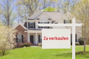 View of two-storey detached house with clinker brick and rendered façade on well-tended front garden and for sale sign