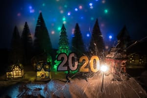 Frontansicht eines beleuchteten Miniatur-Weihnachtsdorfs mit Spielzeughäusern und funkenstrotzender 2020-Deko im Schnee