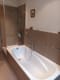 Innenaufnahme eines modernen Badezimmers mit eingelassener Badewanne braunen Wandfliesen und Glas-Duschabtrennung