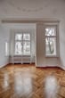 Innenansicht Altbauwohnung mit Fischgrätparkett Stuckdecken und drei hohen Fenstern mit Blick ins Grüne