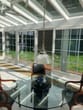 Varanda de inverno de uma casa unifamiliar em vista lateral com mesa redonda de vidro, cadeiras, candeeiro suspenso e vista para o jardim