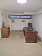 arrecadação com janela alta e estreita vista lateral secretária antiga de madeira escura monitor e prateleira