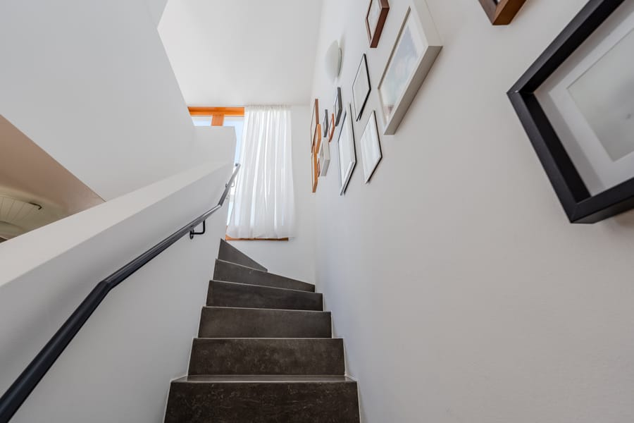 Eleganter Treppenaufgang mit Tageslicht und klarer Linienführung - Stilvolles Townhouse nahe Uferpromenade mit Dachterrassen und durchdachtem Grundriss