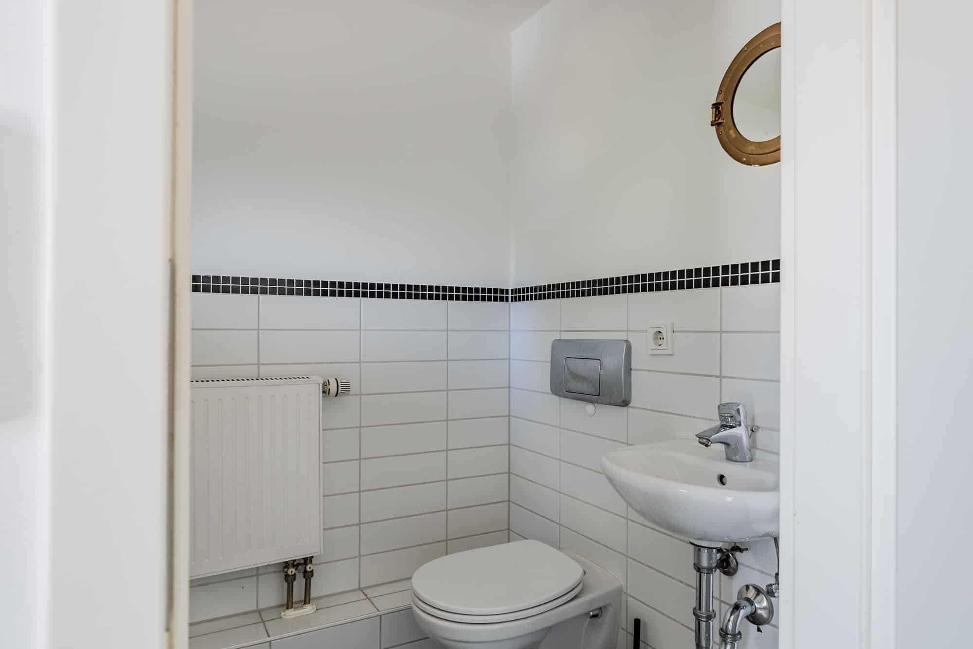 Kompaktes Gäste-WC mit weißer Fliesenausstattung - Bezugsfrei & renoviert 2025: 6-Zimmer-Townhouse an der Rummelsburger Bucht