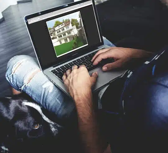 dreigeschossige Villa in Frontalansicht mit Satteldach, Balkon und großem Garten