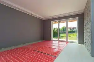 Innenansicht Einfamilienhaus mit Terrassentüren zum Garten sichtbare Bodenheizung rote Folie Steinwand