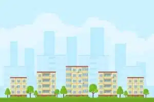 Frontansicht mehrerer gelber Wohngebäude mit Balkonen Satellitenschüsseln und Baumbepflanzung vor Stadtsilhouette