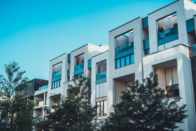 Moderner mehrgeschossiger Wohnkomplex mit kubischer Architektur, weißen Fassaden und verglasten Balkonen aus Frontperspektive