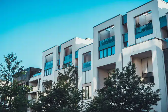 Moderner mehrgeschossiger Wohnkomplex mit kubischer Architektur, weißen Fassaden und verglasten Balkonen aus Frontperspektive